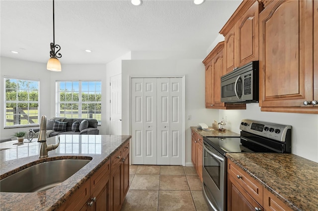 15350 Arabian Way, Montverde, FL 34756 - kitchen featuring stainless steel appliances, brown cabinets, dark stone countertops, decorative light fixtures, and a textured ceiling