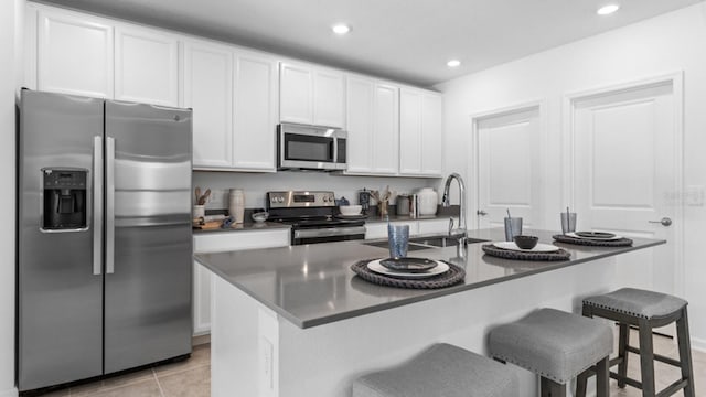 7898 Poplin St, Kissimmee, FL 34747 - kitchen with stainless steel appliances, a breakfast bar area, white cabinetry, dark countertops, and a kitchen island with sink