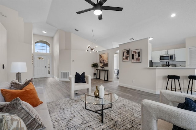 2898 Picadilly Cir, Kissimmee, FL 34747 - living area with light wood-style floors, lofted ceiling, a ceiling fan, arched walkways, and a chandelier