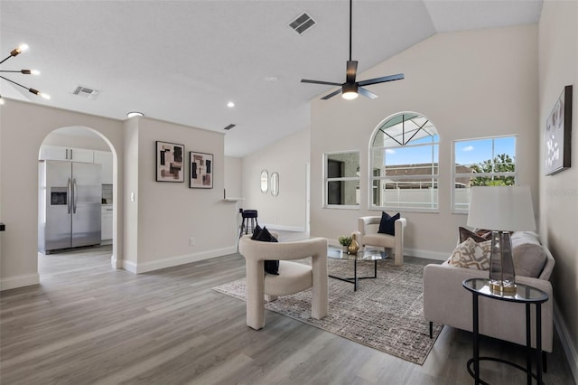 2898 Picadilly Cir, Kissimmee, FL 34747 - living room featuring arched walkways, wood finished floors, ceiling fan, high vaulted ceiling, and a chandelier