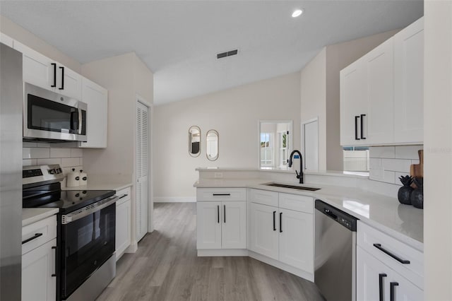 2898 Picadilly Cir, Kissimmee, FL 34747 - kitchen with stainless steel appliances, decorative backsplash, light wood-type flooring, white cabinets, and lofted ceiling