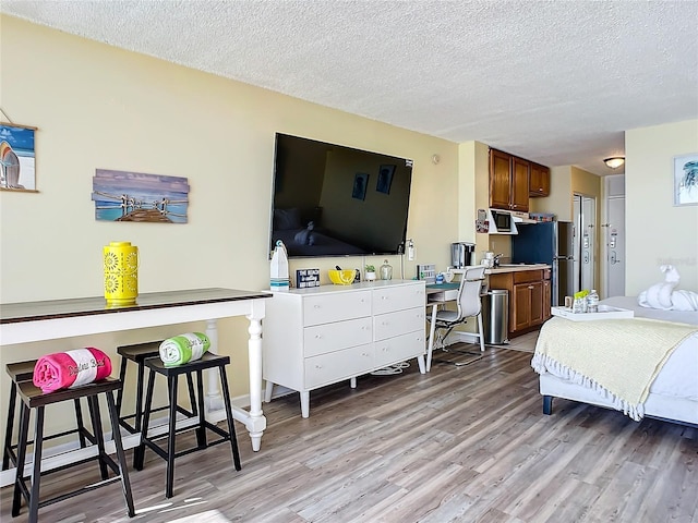 701 S Atlantic Ave Unit 504, Daytona Beach, FL 32118 - bedroom featuring light wood-style flooring, a textured ceiling, and freestanding refrigerator