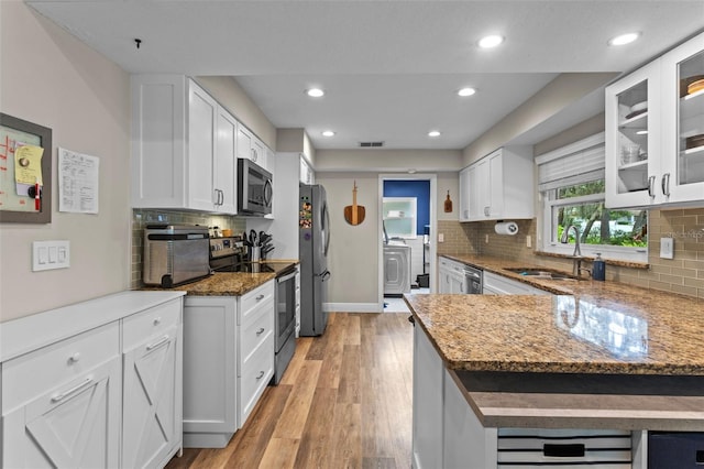 11815 Lake Susan, Clermont, FL 34711 - kitchen with appliances with stainless steel finishes, washer / clothes dryer, decorative backsplash, white cabinetry, and recessed lighting
