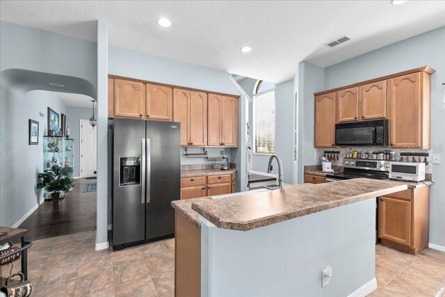 523 Lake Davenport Cir, Davenport, FL 33837 - kitchen with refrigerator with ice dispenser, black microwave, stainless steel electric range oven, an island with sink, and recessed lighting