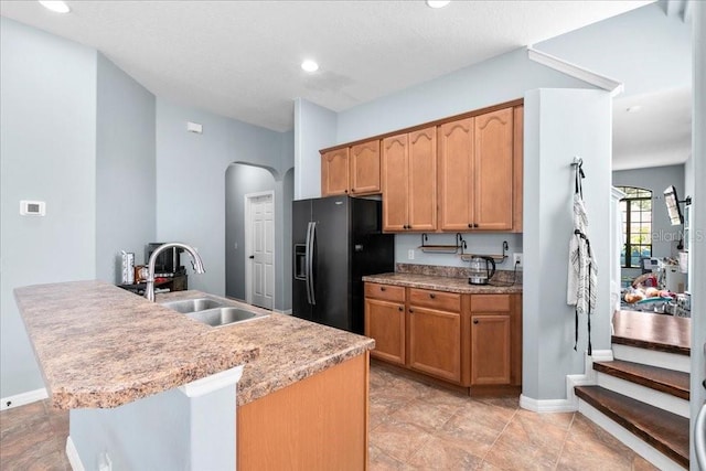 523 Lake Davenport Cir, Davenport, FL 33837 - kitchen featuring black fridge with ice dispenser, arched walkways, recessed lighting, light countertops, and a center island with sink