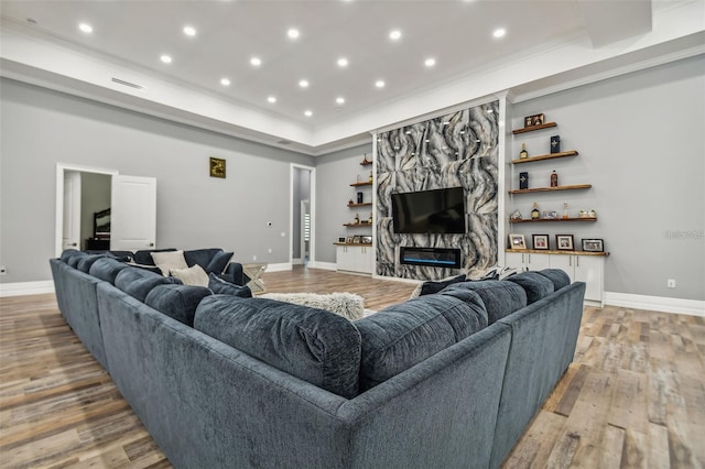 15715 Trousdale St, Clermont, FL 34715 - living room featuring a high end fireplace, light wood-style floors, recessed lighting, a raised ceiling, and ornamental molding