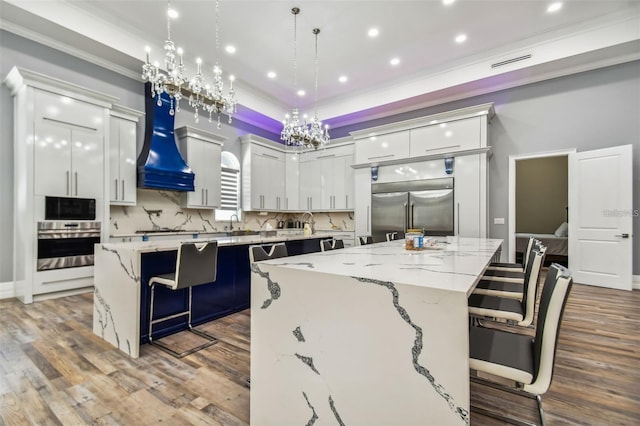 15715 Trousdale St, Clermont, FL 34715 - kitchen featuring a large island, appliances with stainless steel finishes, a kitchen bar, premium range hood, and backsplash