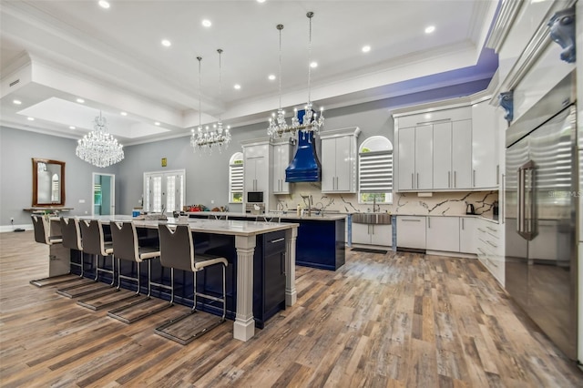 15715 Trousdale St, Clermont, FL 34715 - kitchen featuring a large island, wood finished floors, a tray ceiling, crown molding, and recessed lighting