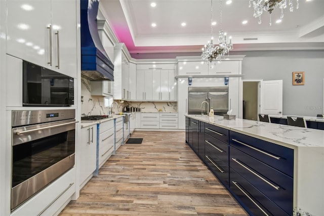 15715 Trousdale St, Clermont, FL 34715 - kitchen featuring appliances with stainless steel finishes, custom exhaust hood, white cabinets, crown molding, and light wood-style floors