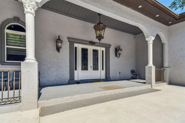 15715 Trousdale St, Clermont, FL 34715 - view of exterior entry featuring a porch, stucco siding, and french doors