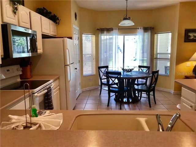 7763 Tosteth St, Kissimmee, FL 34747 - kitchen with white electric range, stainless steel microwave, light tile patterned floors, and hanging light fixtures