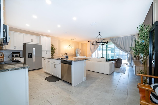 1660 Tropical Palms Cir, Kissimmee, FL 34747 - kitchen featuring stainless steel appliances, dark stone counters, white cabinets, decorative backsplash, and hanging light fixtures