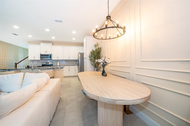 1660 Tropical Palms Cir, Kissimmee, FL 34747 - kitchen featuring appliances with stainless steel finishes, open floor plan, a chandelier, backsplash, and a decorative wall