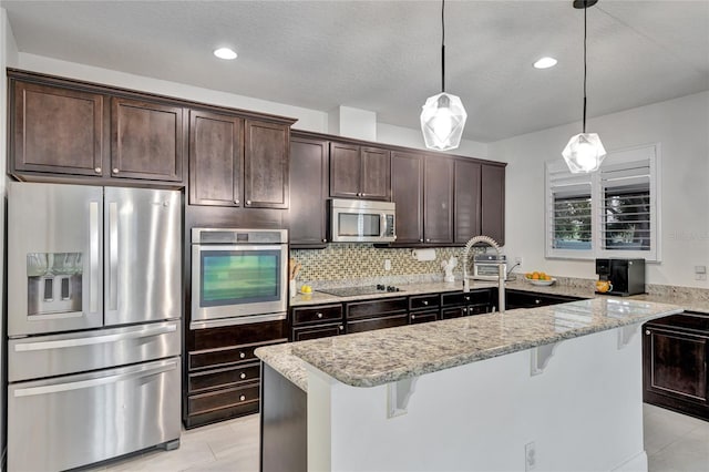 8827 Arrabida Ln, Orlando, FL 32836 - kitchen featuring appliances with stainless steel finishes, dark brown cabinetry, a breakfast bar area, light stone countertops, and recessed lighting