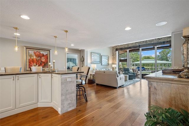 9070 Ron Den Ln, Windermere, FL 34786 - kitchen with light wood finished floors, dark countertops, white cabinetry, recessed lighting, and pendant lighting