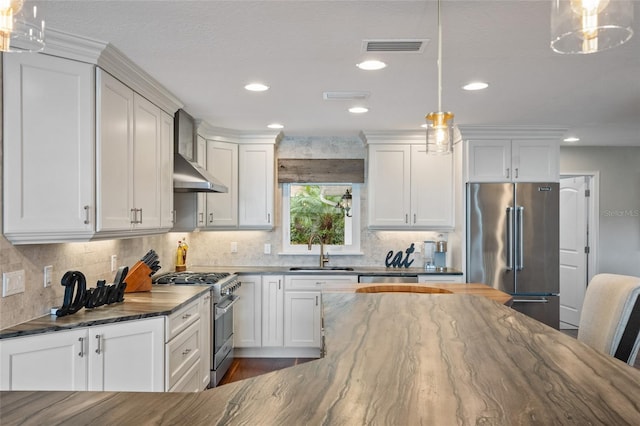 9070 Ron Den Ln, Windermere, FL 34786 - kitchen featuring premium appliances, wall chimney range hood, dark stone countertops, white cabinets, and recessed lighting
