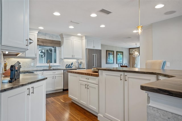 9070 Ron Den Ln, Windermere, FL 34786 - kitchen with stainless steel appliances, white cabinetry, recessed lighting, decorative backsplash, and hanging light fixtures