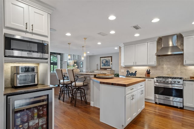 9070 Ron Den Ln, Windermere, FL 34786 - kitchen featuring wall chimney range hood, appliances with stainless steel finishes, butcher block countertops, wine cooler, and tasteful backsplash