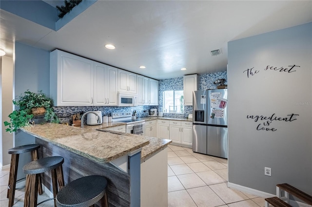 4045 Simkins Ave, North Port, FL 34286 - kitchen featuring white appliances, a peninsula, a kitchen bar, white cabinetry, and recessed lighting
