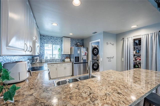 4045 Simkins Ave, North Port, FL 34286 - kitchen with stacked washer / drying machine, appliances with stainless steel finishes, a peninsula, white cabinets, and light stone counters
