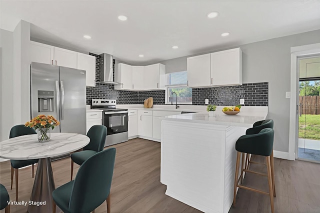 5904 Altec Rd, Orlando, FL 32808 - kitchen with appliances with stainless steel finishes, wall chimney range hood, a peninsula, wood finished floors, and recessed lighting