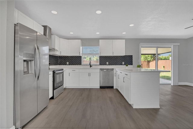 5904 Altec Rd, Orlando, FL 32808 - kitchen with stainless steel appliances, a peninsula, wall chimney exhaust hood, wood finished floors, and recessed lighting