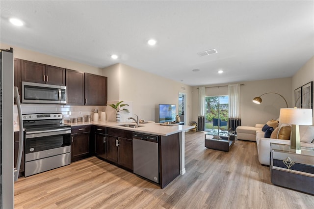 3367 Wynwood Forest Dr, Ocoee, FL 34761 - kitchen featuring stainless steel appliances, open floor plan, dark brown cabinets, a peninsula, and light wood-style floors