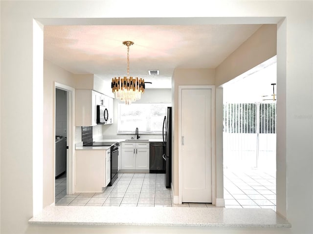 4219 Chateau Rd, Orlando, FL 32808 - kitchen featuring black appliances, light tile patterned floors, a chandelier, pendant lighting, and white cabinets