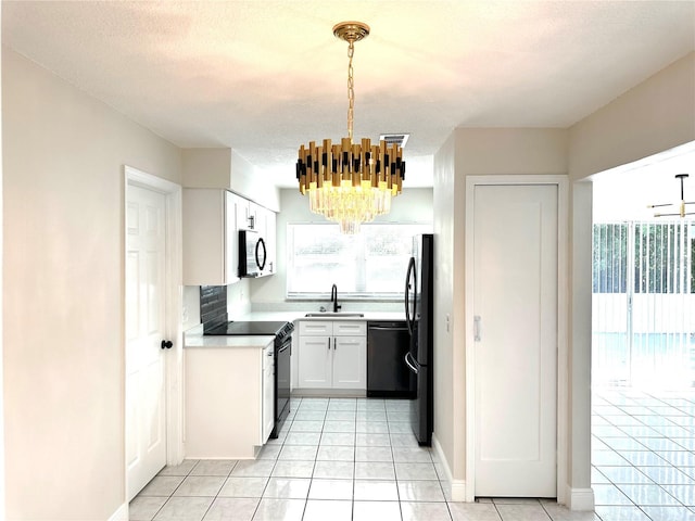 4219 Chateau Rd, Orlando, FL 32808 - kitchen with black appliances, a chandelier, light tile patterned floors, light countertops, and white cabinets