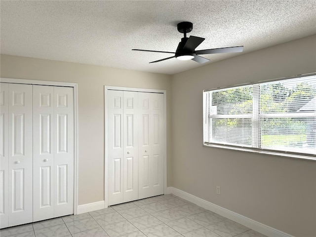 4219 Chateau Rd, Orlando, FL 32808 - unfurnished bedroom with multiple closets, a textured ceiling, light marble finish floors, and ceiling fan
