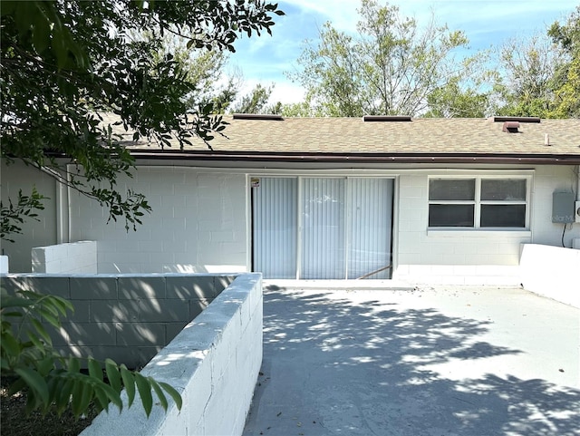 4219 Chateau Rd, Orlando, FL 32808 - doorway to property featuring concrete block siding, a shingled roof, and a patio area