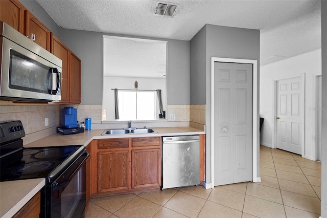 1040 Cannock Dr, Kissimmee, FL 34758 - kitchen with appliances with stainless steel finishes, a textured ceiling, light countertops, backsplash, and light tile patterned floors