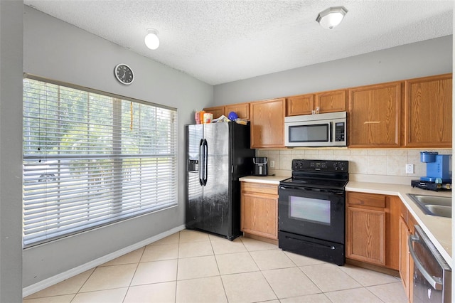 1040 Cannock Dr, Kissimmee, FL 34758 - kitchen featuring black appliances, decorative backsplash, a textured ceiling, light countertops, and brown cabinetry