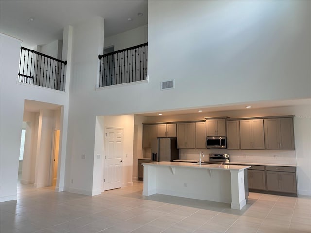 7260 Dilly Lake Ave, Groveland, FL 34736 - kitchen with stainless steel appliances, gray cabinets, a high ceiling, an island with sink, and light countertops
