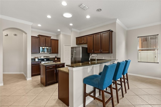 2018 Bay Clover Dr, Winter Garden, FL 34787 - kitchen featuring stainless steel appliances, light tile patterned floors, a peninsula, arched walkways, and ornamental molding