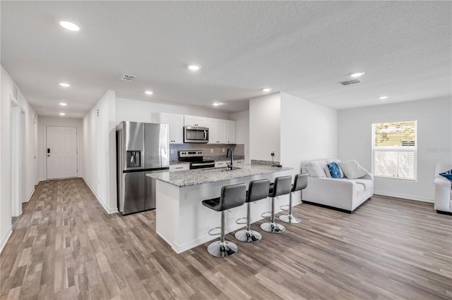 40 Briarvue Ln, Palm Coast, FL 32137 - kitchen with appliances with stainless steel finishes, light wood-type flooring, a breakfast bar, open floor plan, and recessed lighting