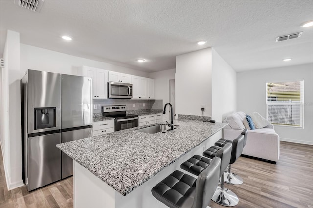 40 Briarvue Ln, Palm Coast, FL 32137 - kitchen with stainless steel appliances, a breakfast bar area, white cabinetry, light wood-style flooring, and a peninsula