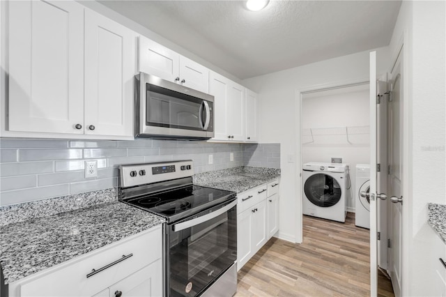40 Briarvue Ln, Palm Coast, FL 32137 - kitchen featuring appliances with stainless steel finishes, washer and dryer, light wood-style flooring, white cabinets, and light stone counters