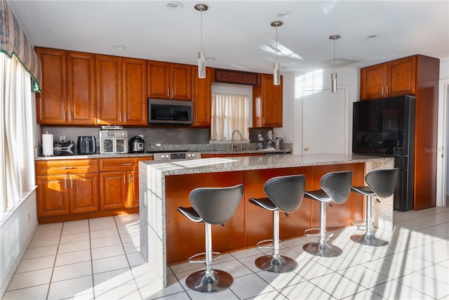1208 Sandestin Way, Orlando, FL 32824 - kitchen featuring stainless steel appliances, decorative backsplash, a center island, and brown cabinetry