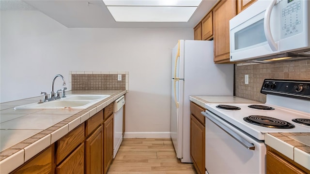 6019 Windhover Dr Unit C10-2, Orlando, FL 32819 - kitchen featuring tile countertops, white appliances, brown cabinetry, backsplash, and light wood-style floors
