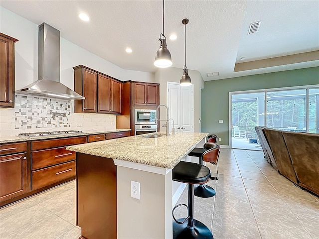 297 Shadow Ridge Trl, Ponte Vedra, FL 32081 - kitchen with wall chimney exhaust hood, stainless steel appliances, backsplash, light stone counters, and a center island with sink