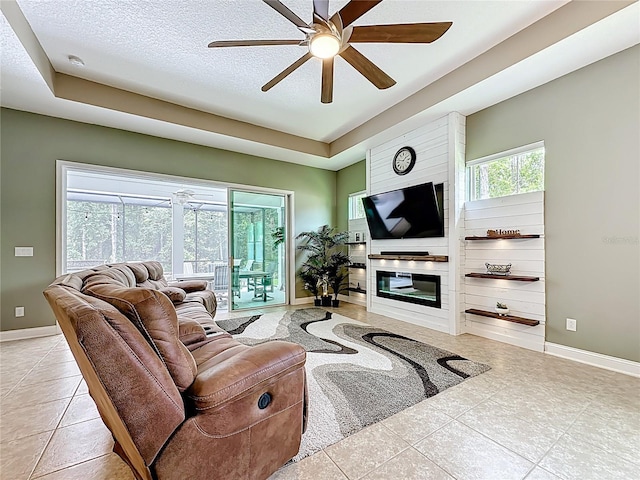 297 Shadow Ridge Trl, Ponte Vedra, FL 32081 - living room featuring a raised ceiling, ceiling fan, light tile patterned floors, a large fireplace, and a textured ceiling