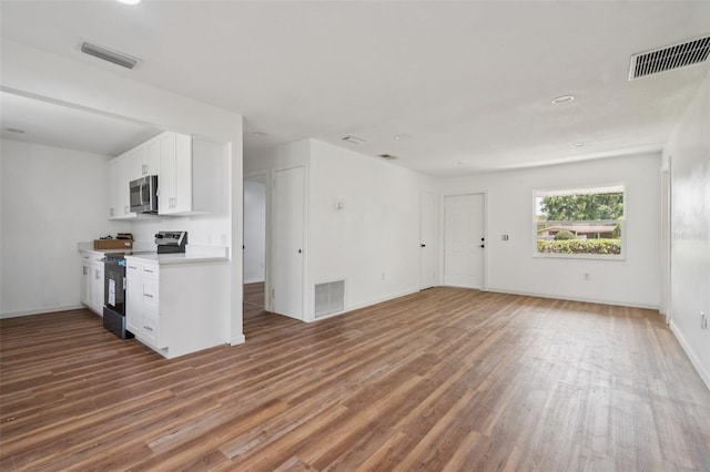 201 E 7th St, Chuluota, FL 32766 - kitchen with range with electric cooktop, stainless steel microwave, light wood-style floors, white cabinetry, and light countertops