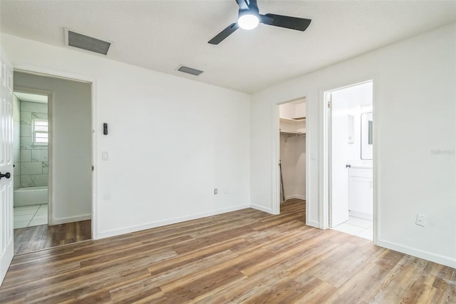 201 E 7th St, Chuluota, FL 32766 - unfurnished bedroom featuring a spacious closet, light wood finished floors, connected bathroom, and a ceiling fan