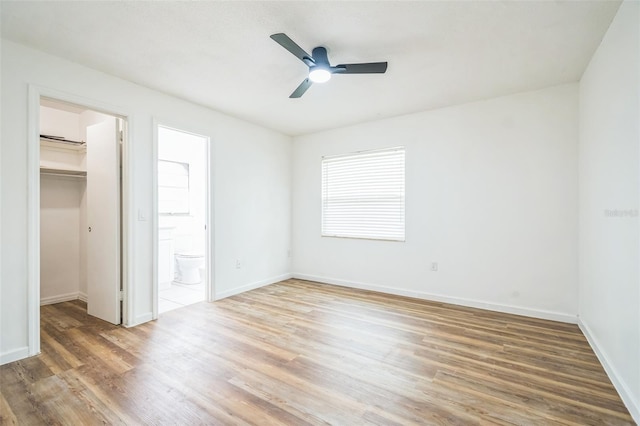 201 E 7th St, Chuluota, FL 32766 - unfurnished bedroom with a walk in closet, wood finished floors, ensuite bath, and a ceiling fan
