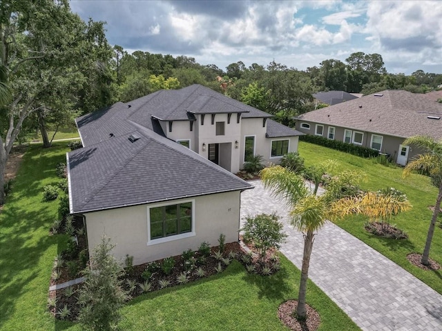 17 Old Oak Dr N, Palm Coast, FL 32137 - view of side of home with decorative driveway, stucco siding, a shingled roof, and a lawn