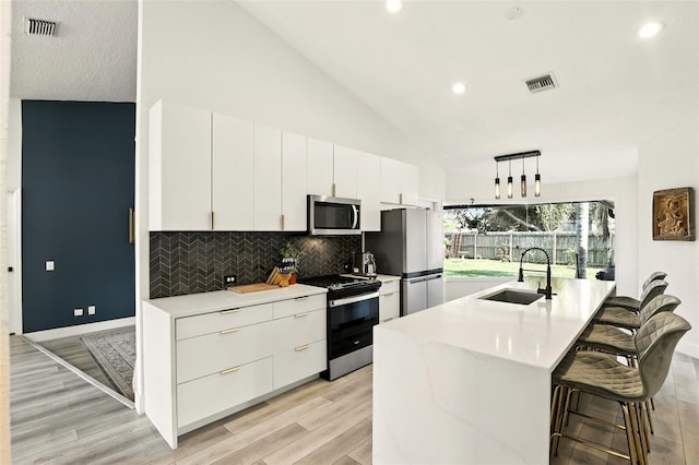 960 Falls Trl, Malabar, FL 32950 - kitchen with stainless steel appliances, light countertops, white cabinets, decorative backsplash, and light wood finished floors