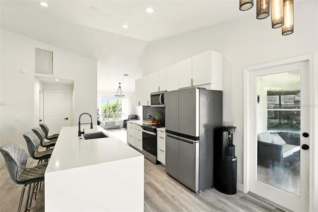 960 Falls Trl, Malabar, FL 32950 - kitchen with appliances with stainless steel finishes, light wood-style flooring, white cabinetry, a kitchen bar, and lofted ceiling