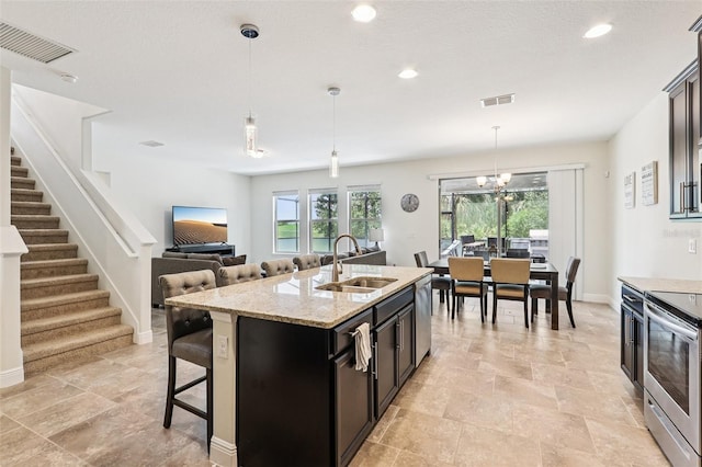 1833 Benoit Ter, Davenport, FL 33837 - kitchen featuring appliances with stainless steel finishes, a center island with sink, a breakfast bar, hanging light fixtures, and light stone counters
