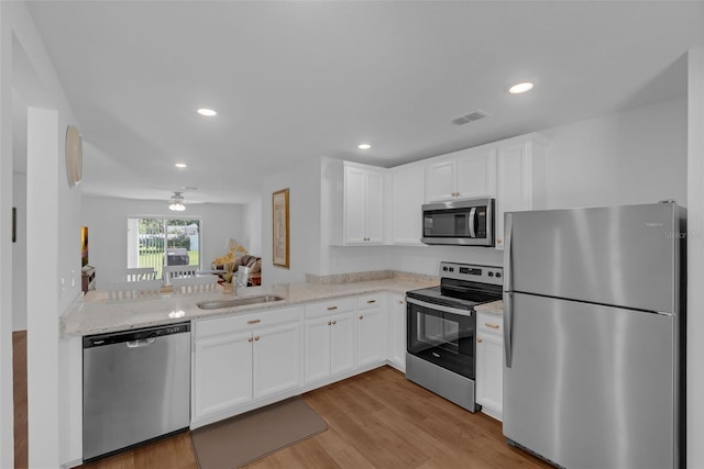 69 Pin Oak Dr, Palm Coast, FL 32164 - kitchen with appliances with stainless steel finishes, light wood-type flooring, white cabinetry, recessed lighting, and light stone countertops